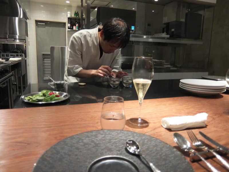 Chef wroring in the open kitchen seen from the counter at Michelin starred restaurant Hiroto in Hiroshima, Japan