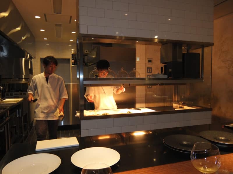 Chefs at work in open kitchen seen from the counter at Michelin starred restaurant Hiroto in Hiroshima, Japan