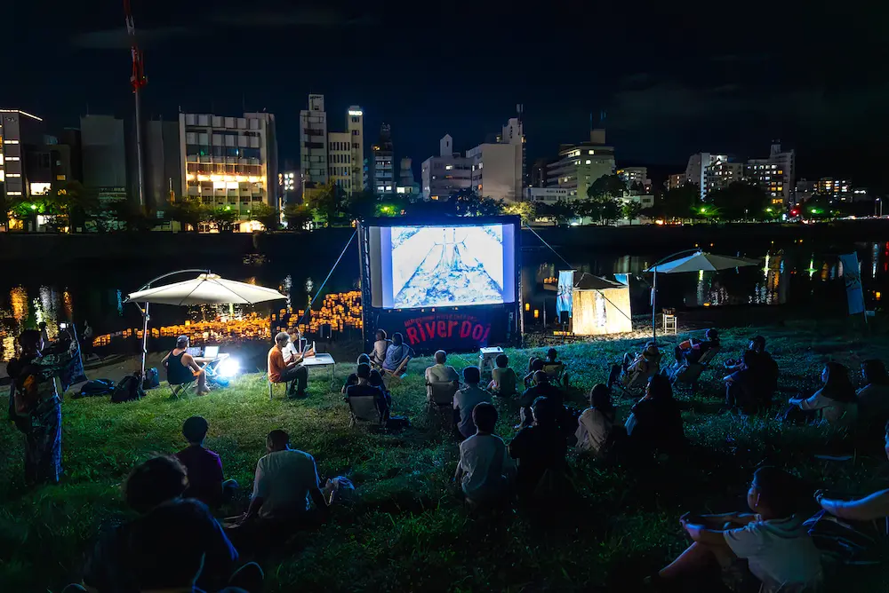 People gather at the riverside on August 6 to honor Toshie Une and perform a kensui offering to the souls of the victims of the A-bomb attack.  